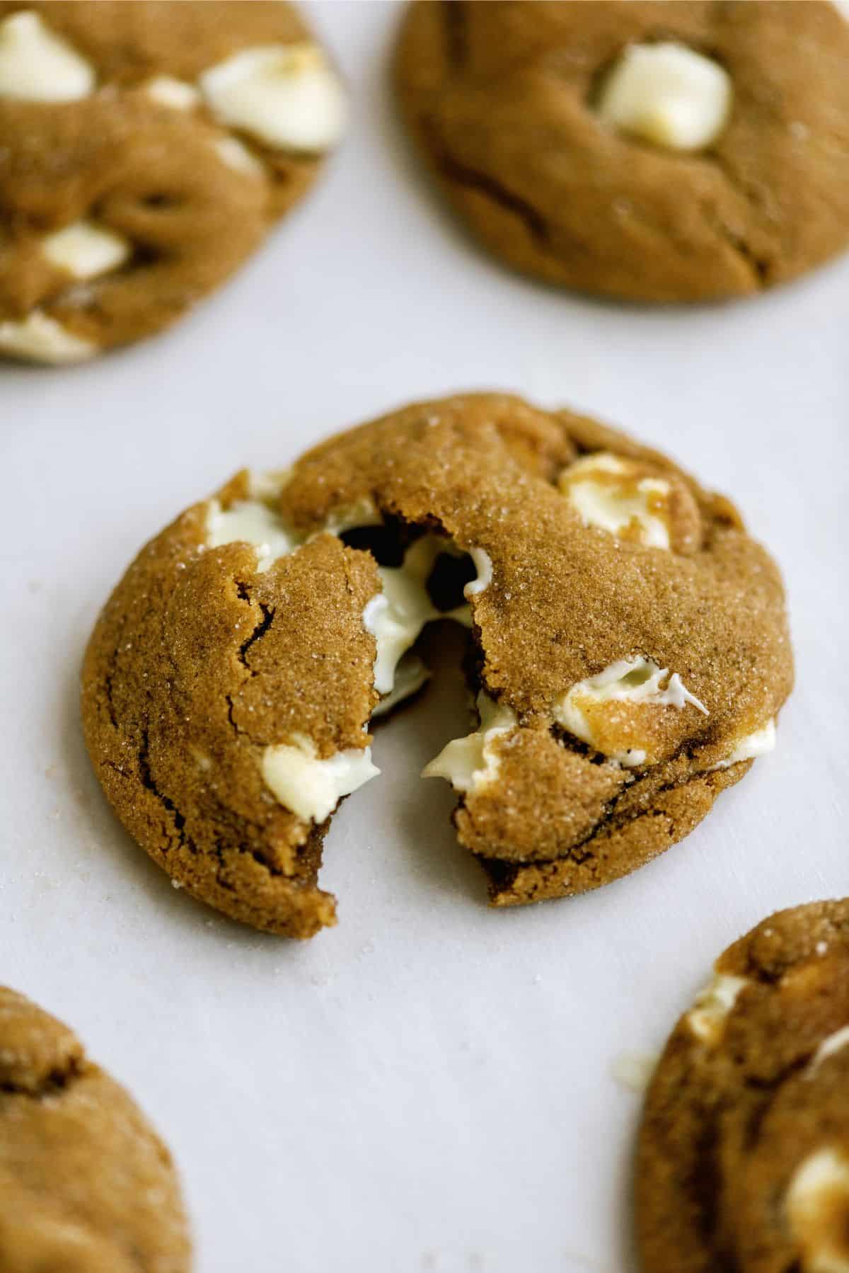 Close up of a White Chocolate Chip Gingerbread Cookie split in half to show the inside. Surrounded by other White Chocolate Chip Gingerbread Cookies.