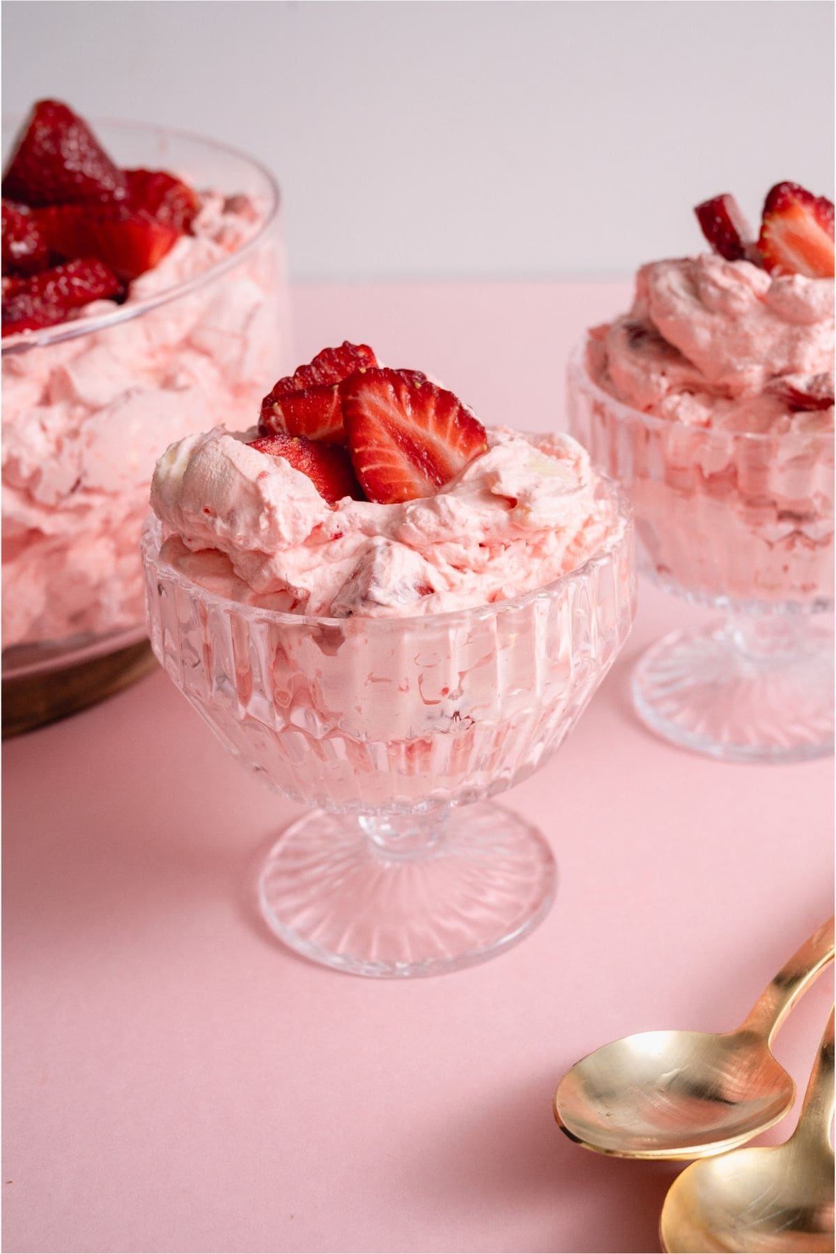 Servings of Strawberry Jello Fluff Salad put into cups topped with fresh strawberries.