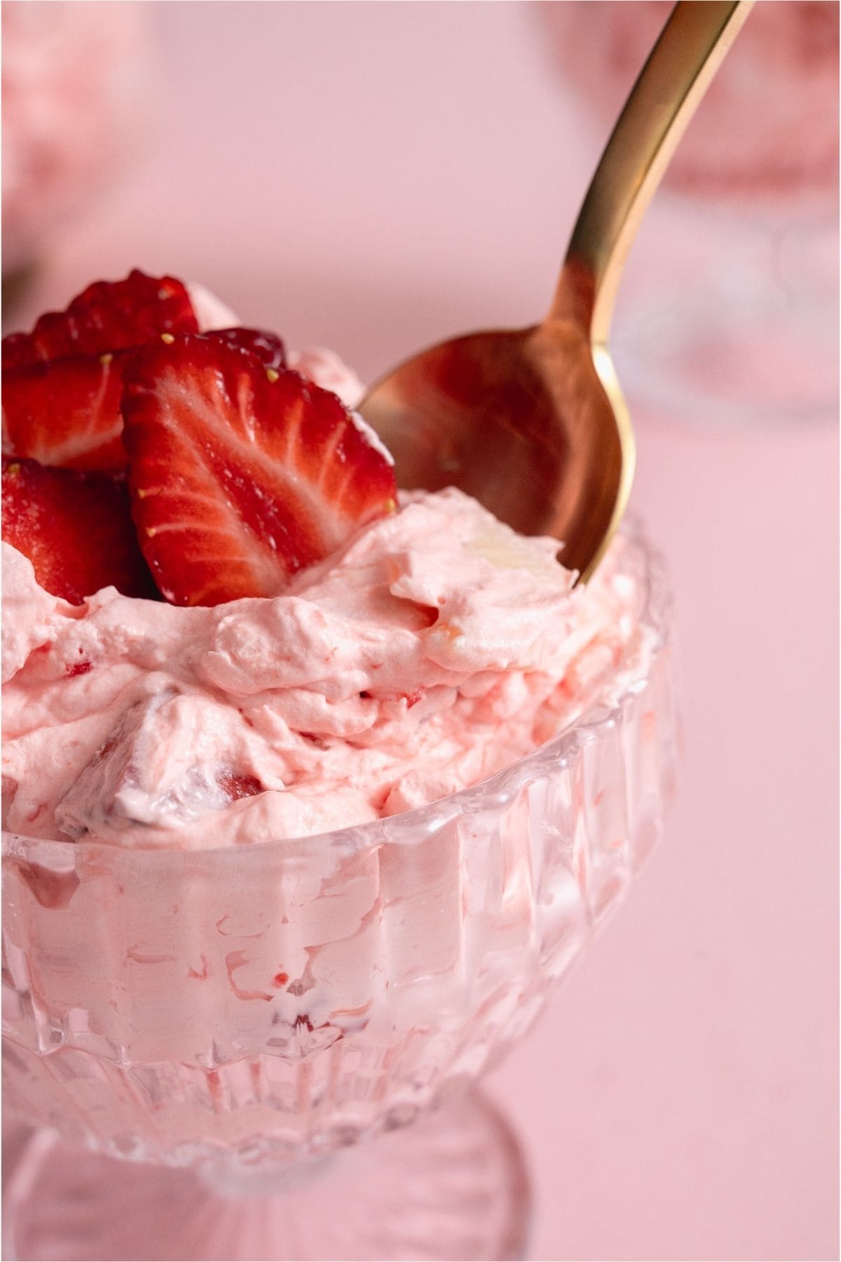 A close up of a cup of Strawberry Jello Fluff Salad with a spoon.