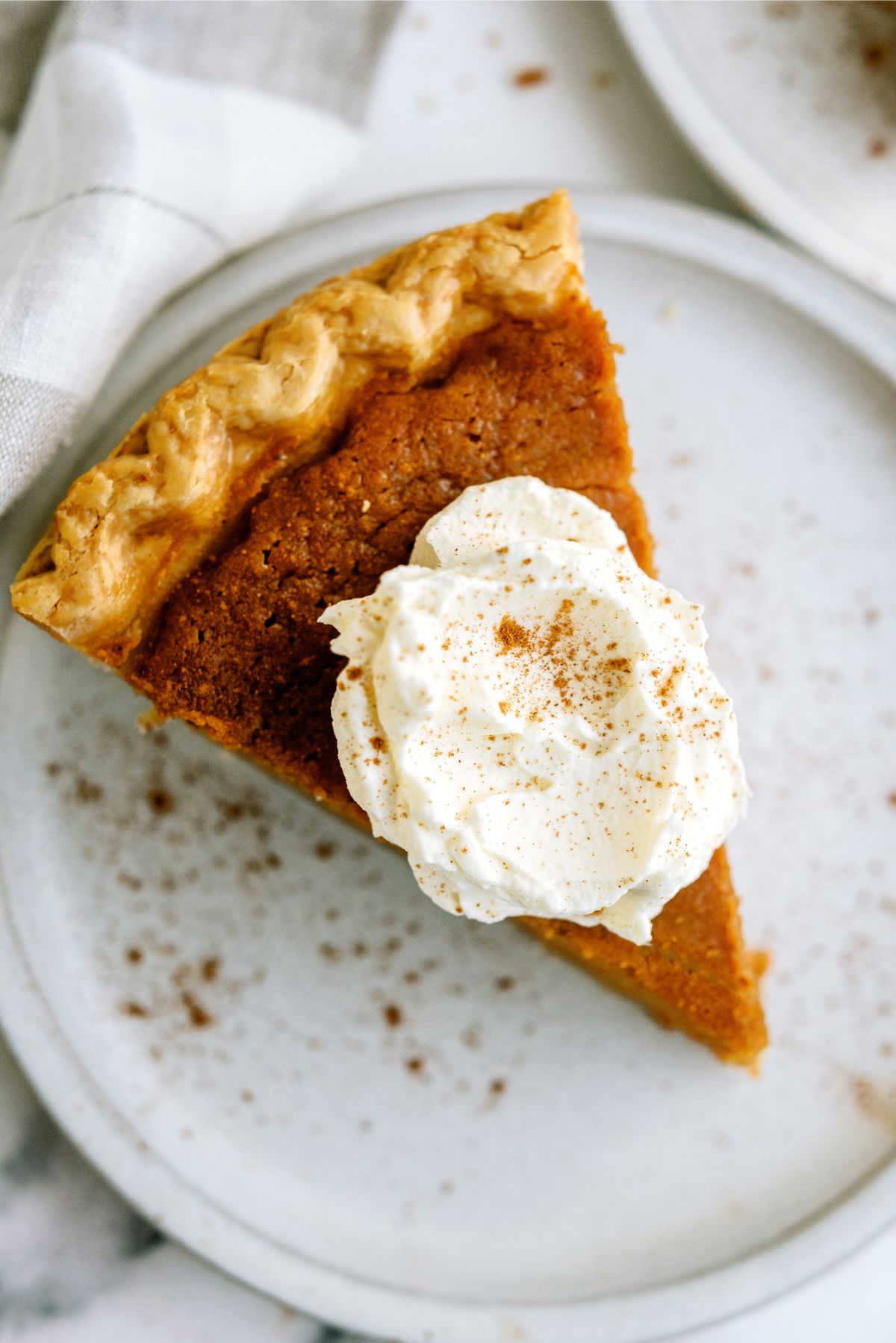 Slice of Sweet Potato Pie on a plate topped with whipped cream