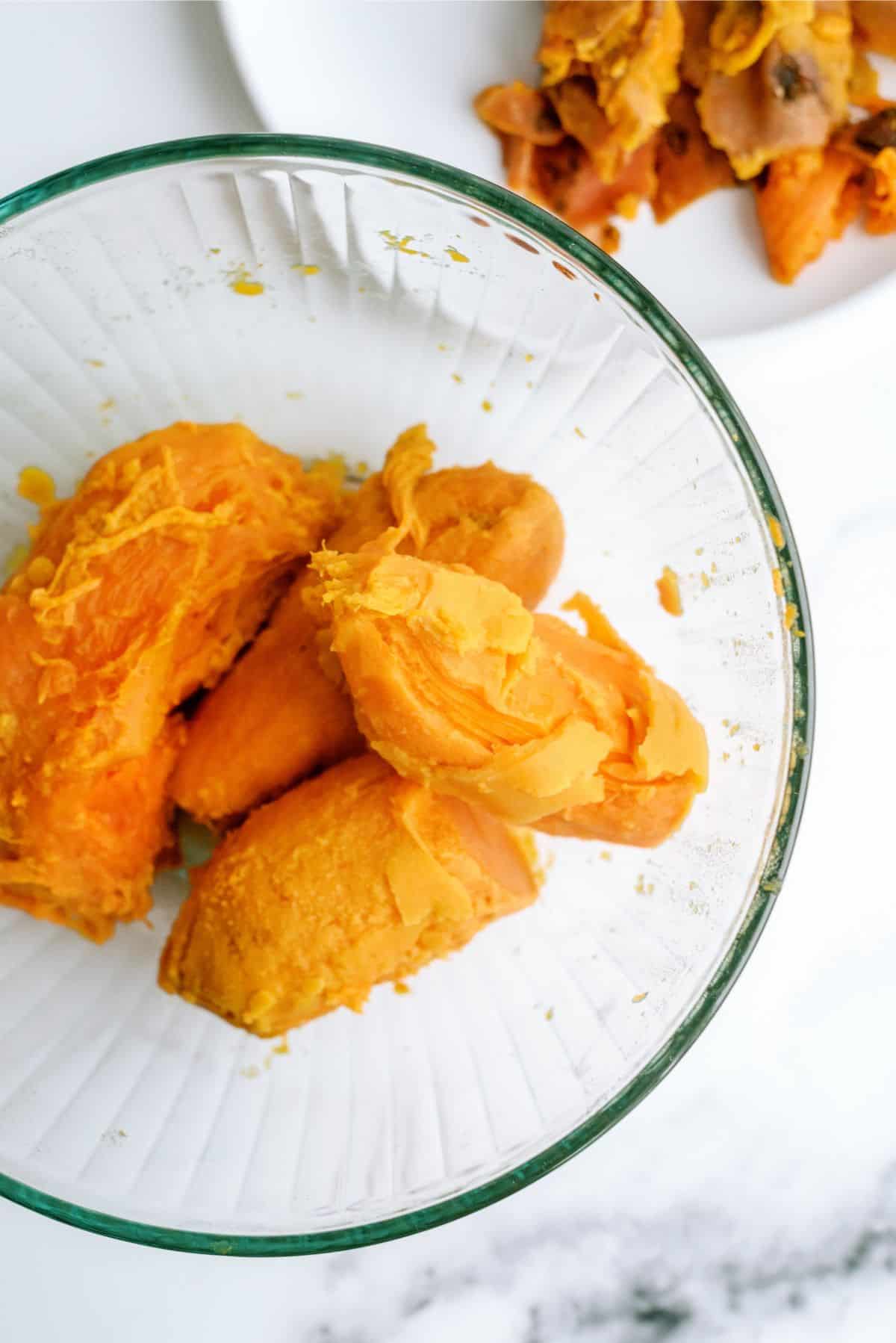 Cooked sweet potatoes with skin removed in glass bowl