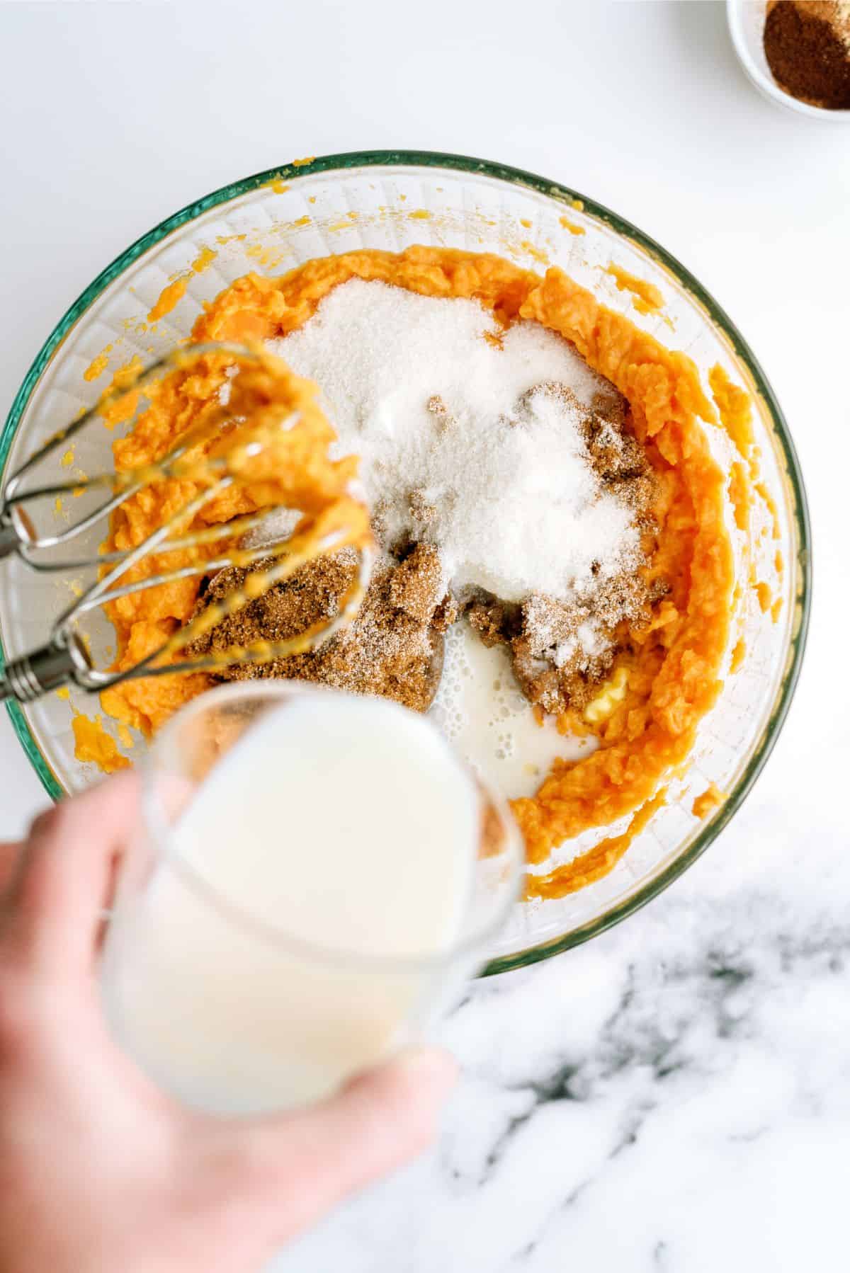 Adding sugar to sweet potato mixture in mixing bowl