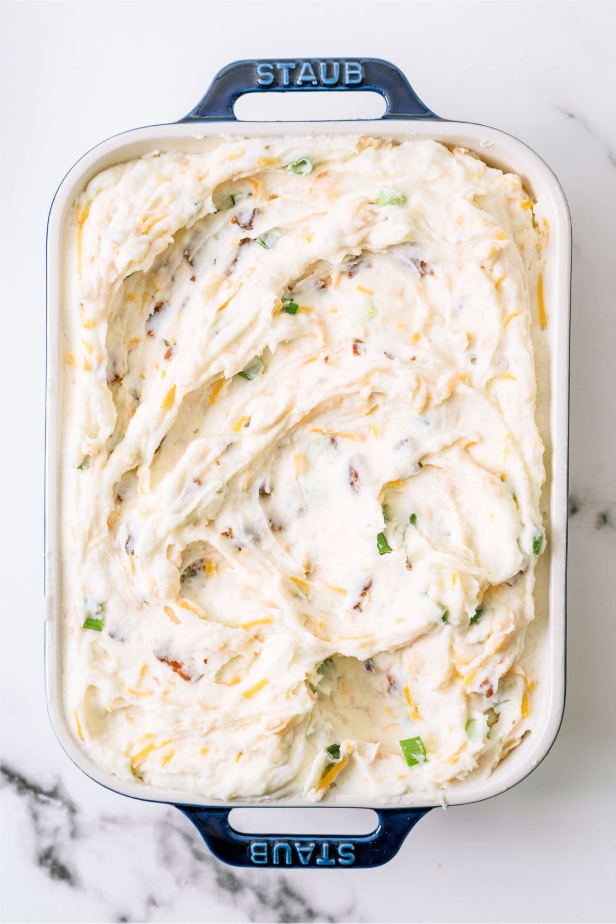 Bottom layer of Twice Baked Potato Casserole spread in glass baking dish.