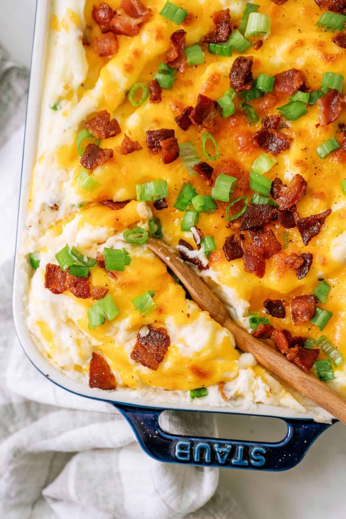 A wooden spoon scooping out a serving of Twice Baked Potato Casserole.