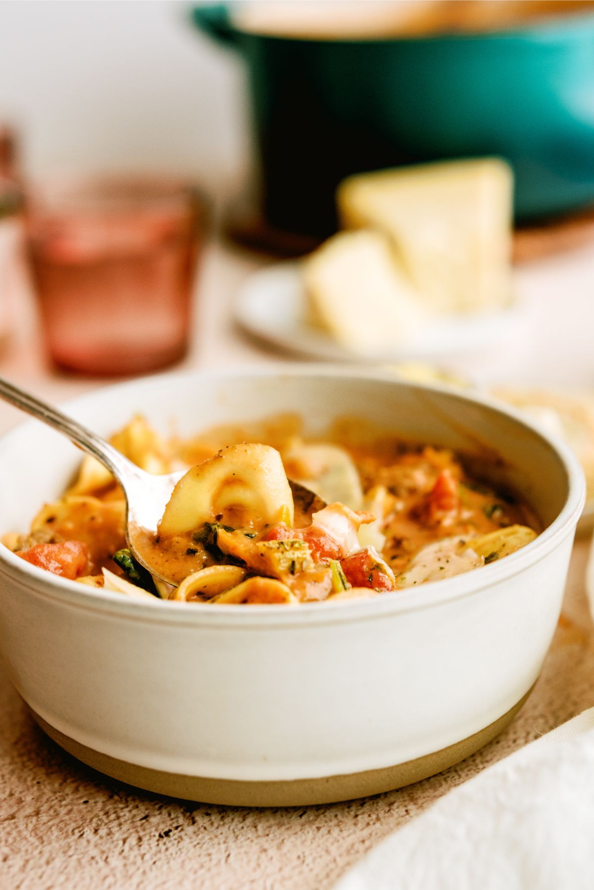 Side view of a bowl of Easy Sausage Tortellini Soup with a spoon