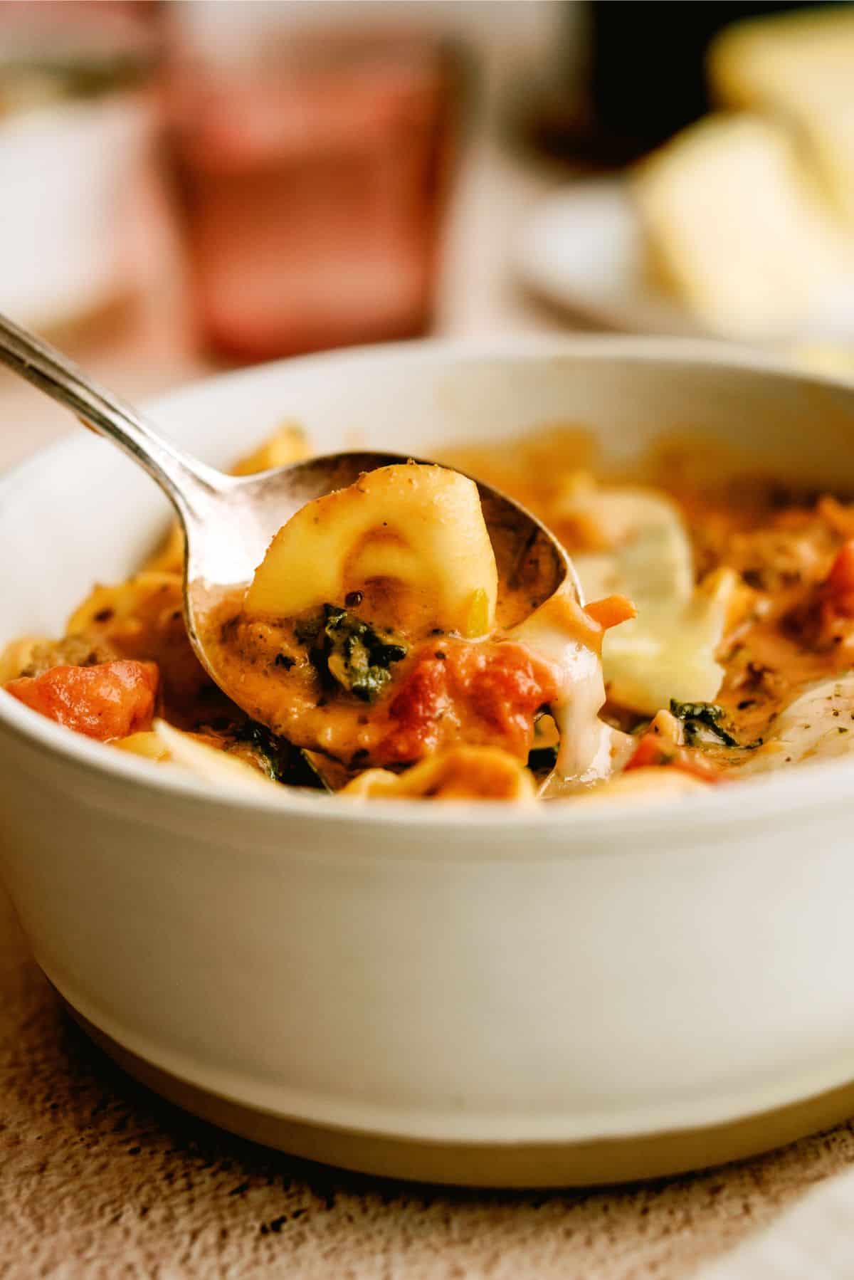 Side view of a bowl of Easy Sausage Tortellini Soup with a spoon