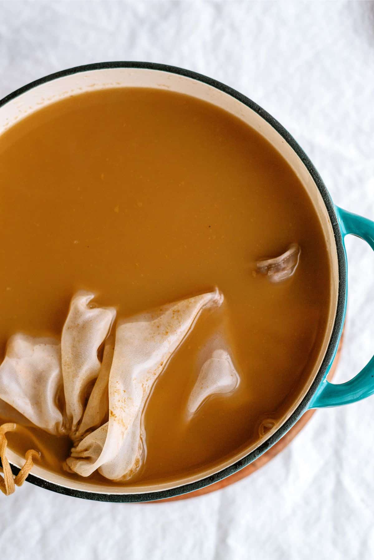 All ingredients to make Grandma’s Warm Spiced Cider in a stock pot with cheesecloth