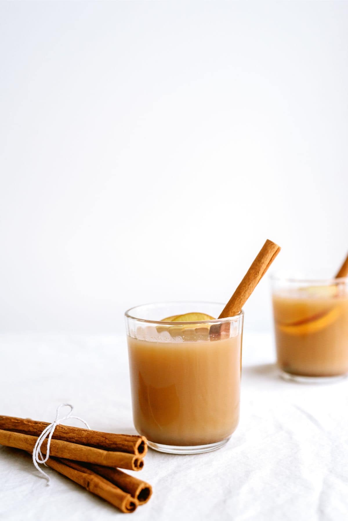 A glass of Grandma’s Warm Spiced Cider with cinnamon sticks