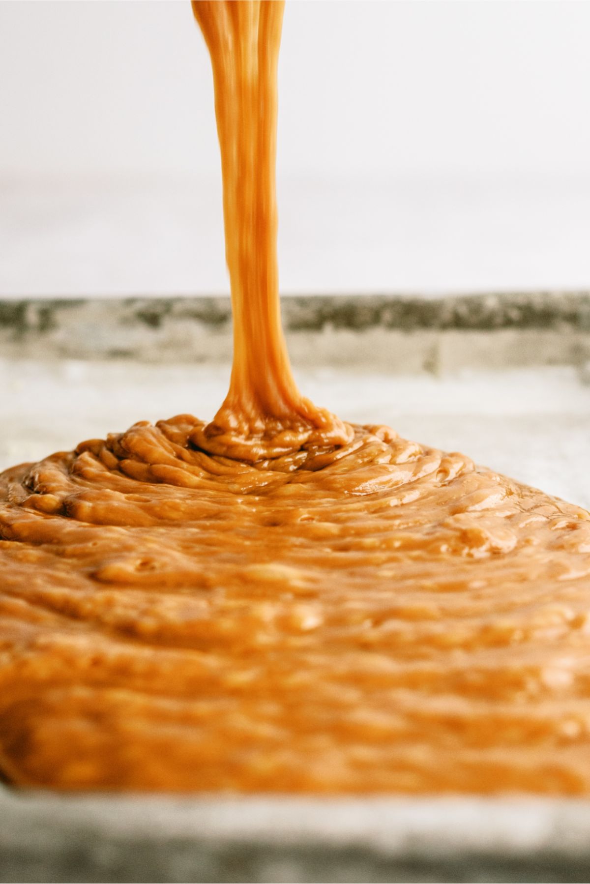 Pouring hot caramel mixture into a greased pan