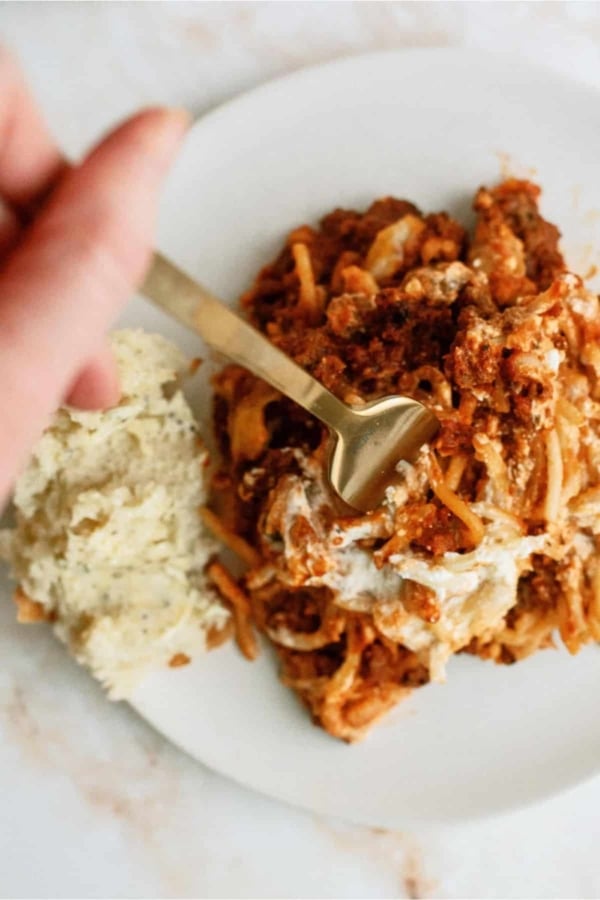 A serving of Million Dollar Casserole (Spaghetti Casserole) on a plate with a fork