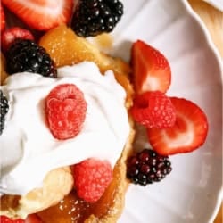 Top view of a serving of Overnight Creme Brulee French Toast Bake on a plate topped with whip cream and berries.