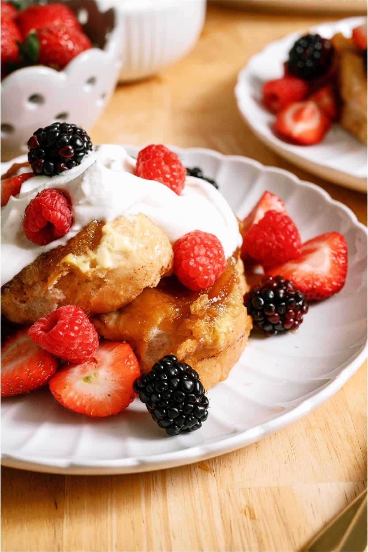 Top view of a serving of Overnight Creme Brulee French Toast Bake on a plate topped with whip cream and berries.