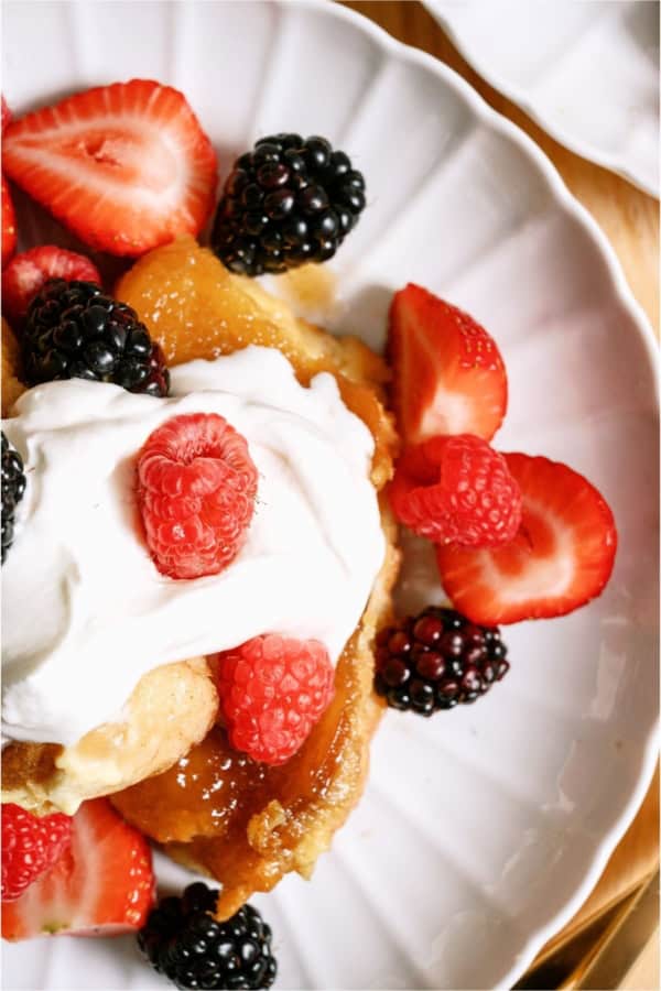 Top view of a serving of Overnight Creme Brulee French Toast Bake on a plate topped with whip cream and berries.