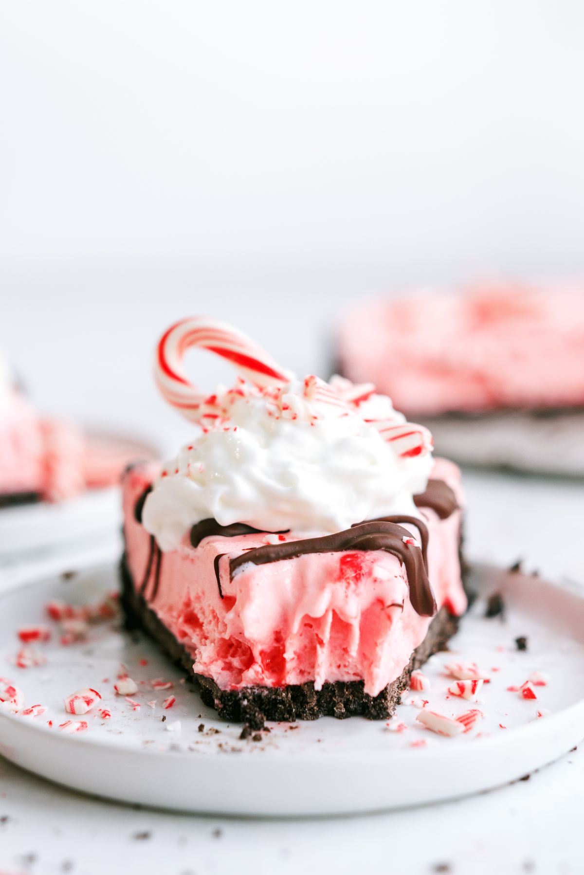 A slice of Peppermint Crunch Ice Cream Pie on a plate with a bite missing out of it.