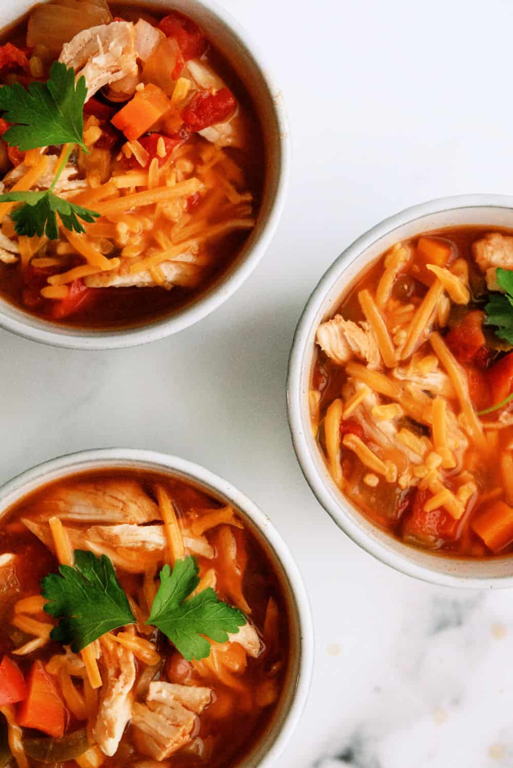 3 bowls of Slow Cooker BBQ Chicken Chili topped with cheese