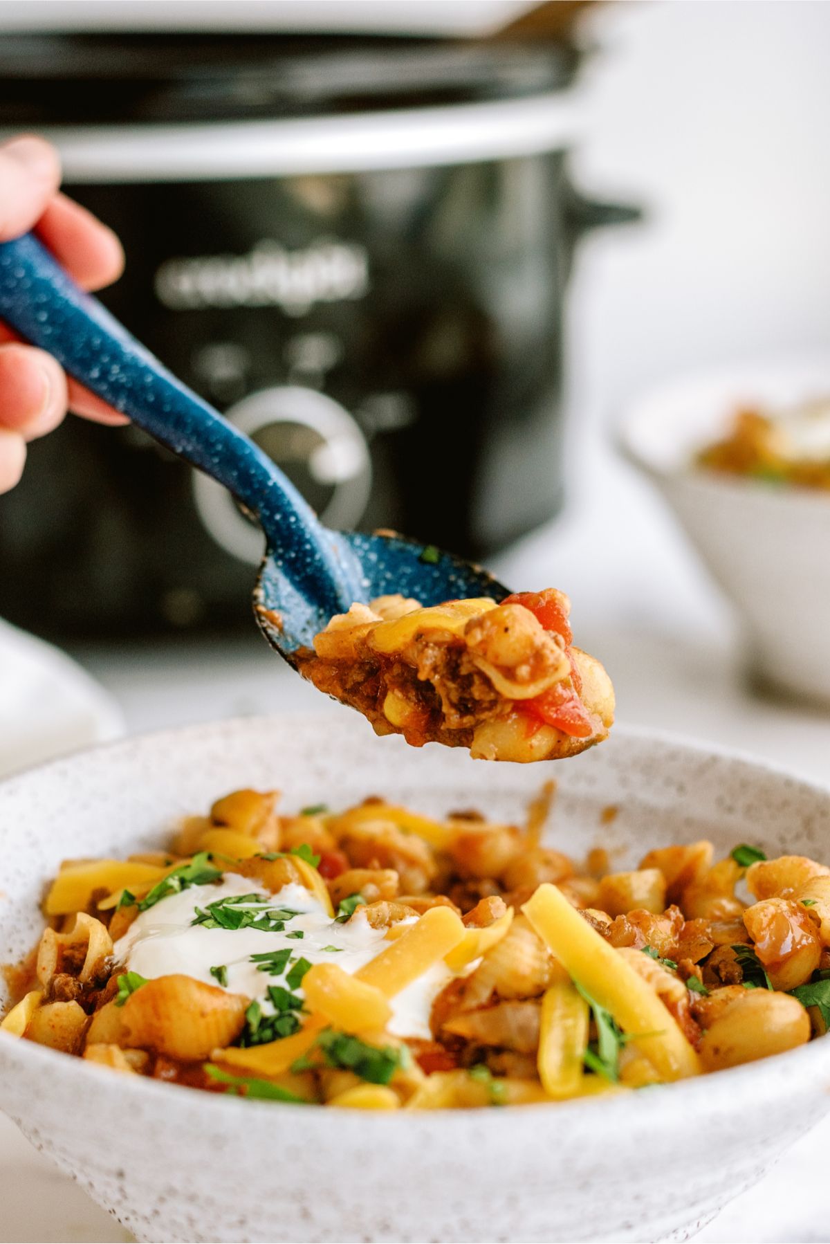 A spoonful being taken out of a bowl full of Slow Cooker Cheesy Beef Taco Pasta