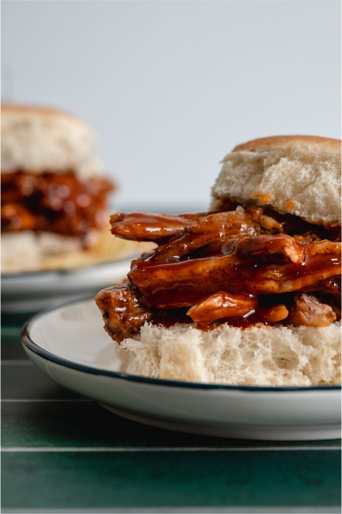 Slow Cooker Smoky BBQ Pulled Pork sandwich on a plate with the top bun off to the side.