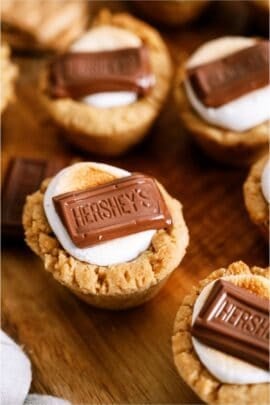 S’mores Cookie Cups sitting on a wooden cutting board.
