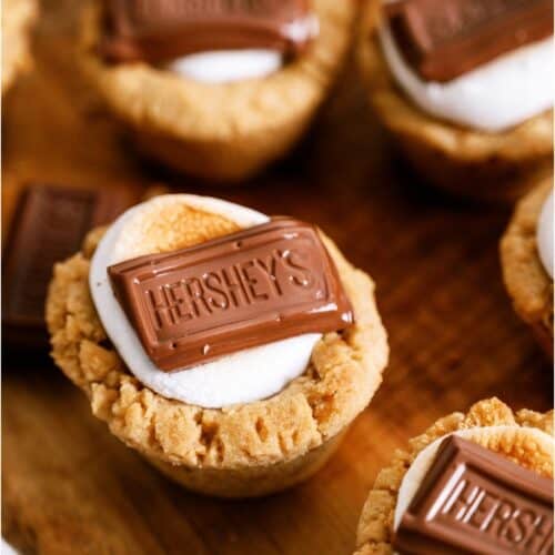 S’mores Cookie Cups sitting on a wooden cutting board.