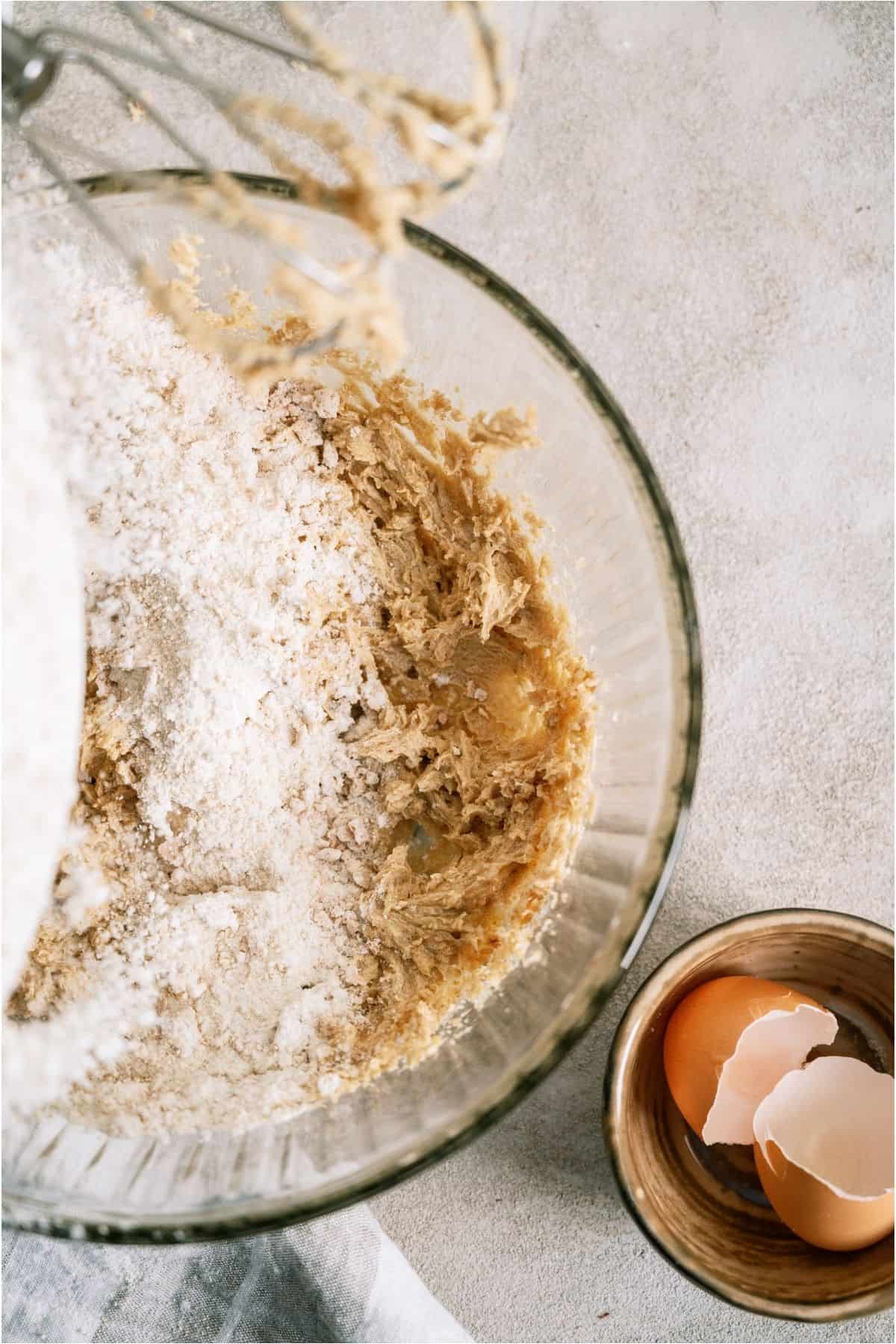 Adding dry ingredients to wet ingredients in a glass mixing bowl.