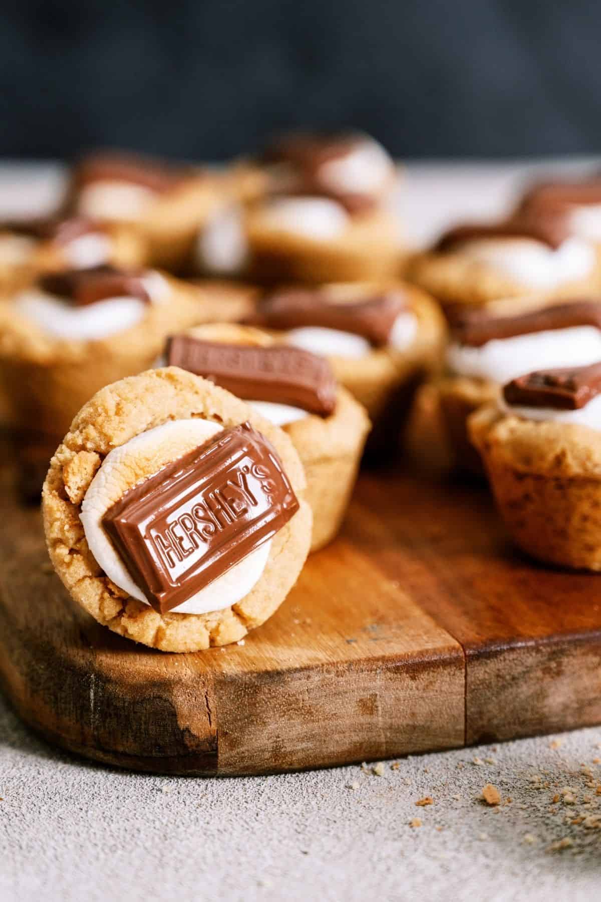 S’mores Cookie Cups on a cutting board with one cookie cup turned on it's side.