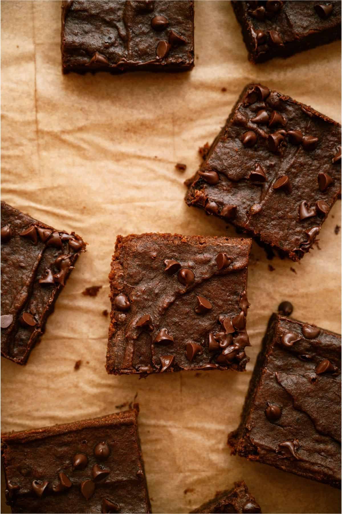 Squares of 2 Ingredient Pumpkin Brownies scattered on parchment paper.