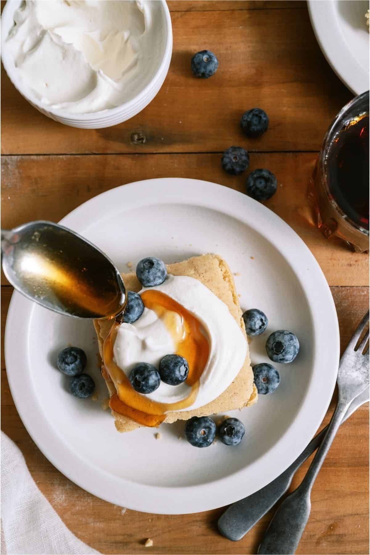 A spoon, spooning syrup on top of a serving of Baked Pancakes.
