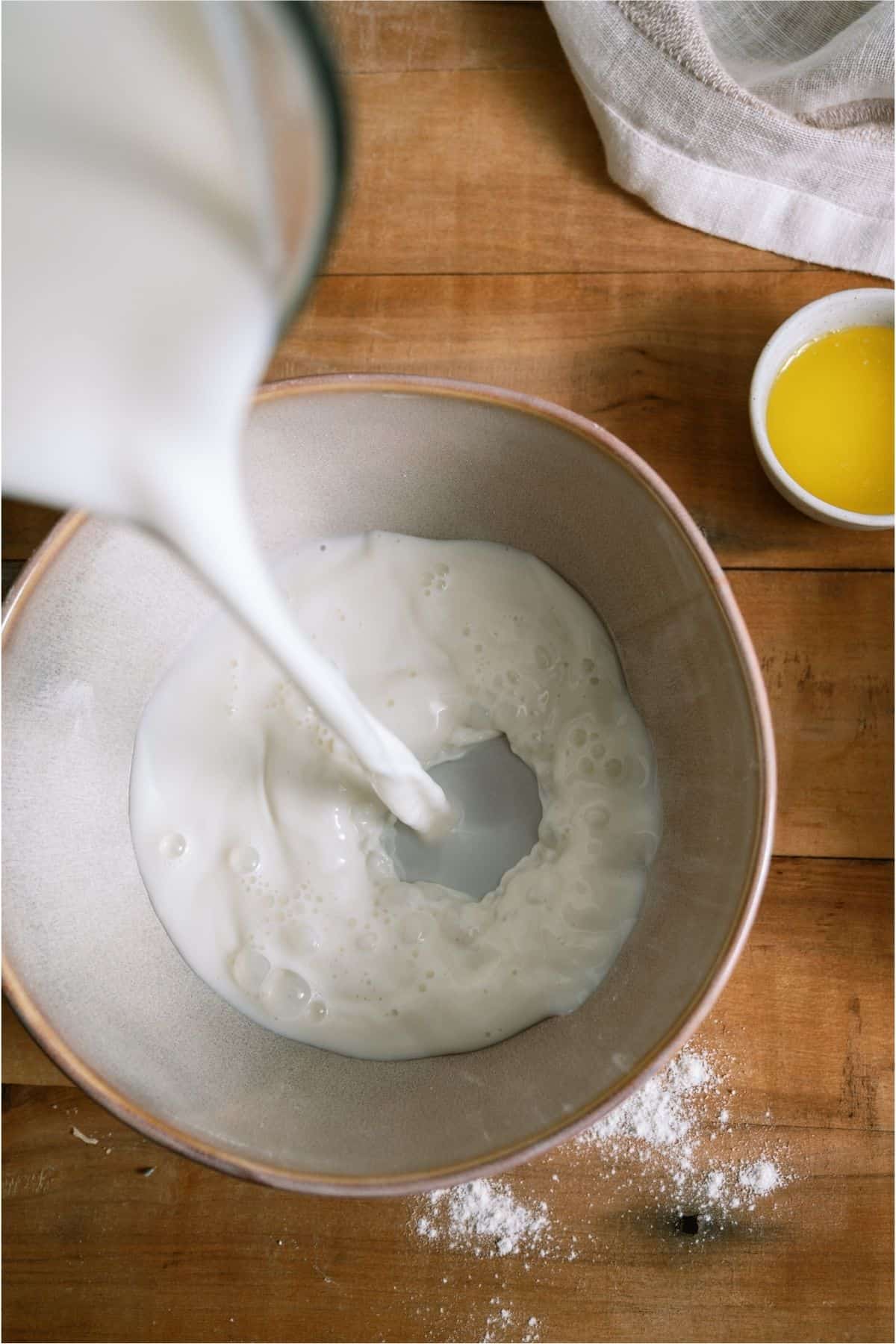 Pouring milk into a large mixing bowl.