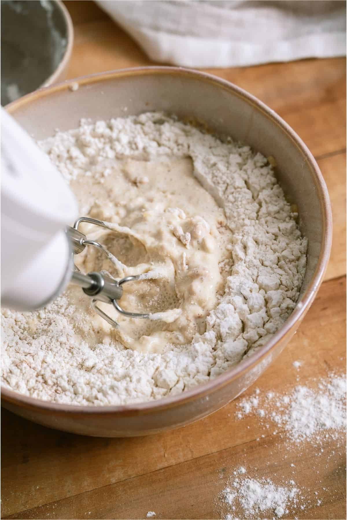 Mixing flour into milk mixture with a hand mixer.