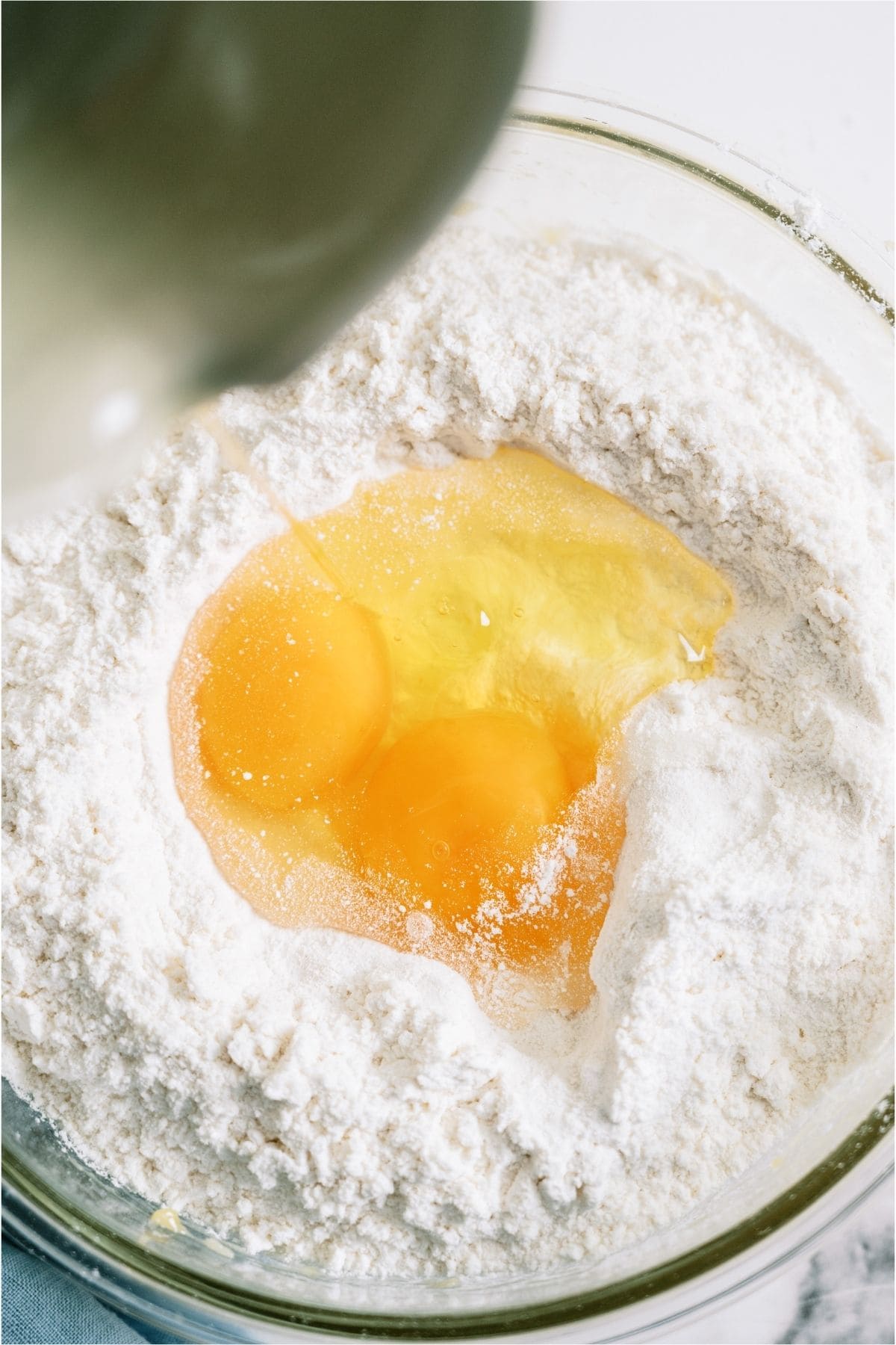 2 eggs added to a white cake mix in a glass mixing bowl.