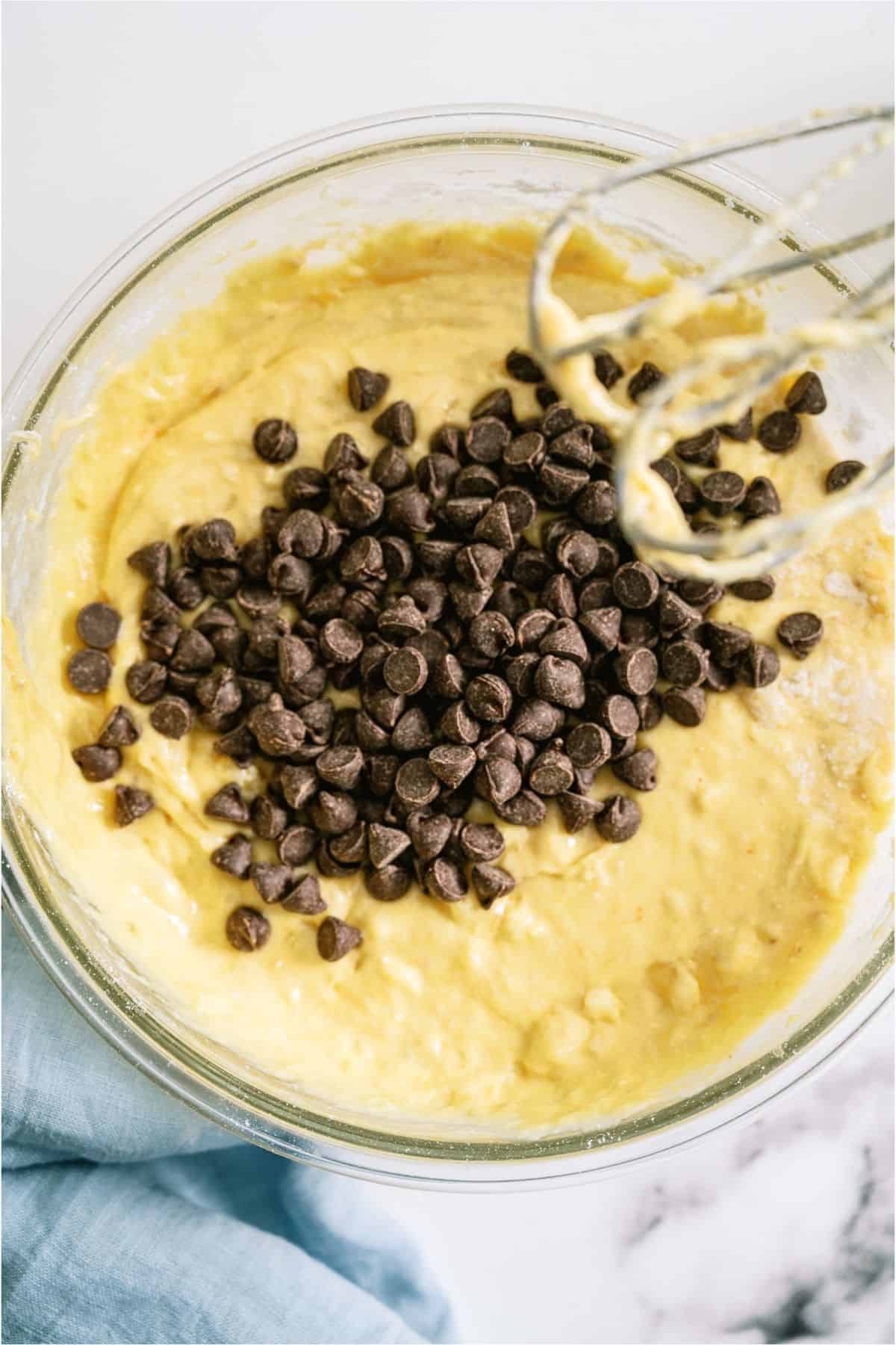 Banana bread batter in a mixing bowl with chocolate chips on top.