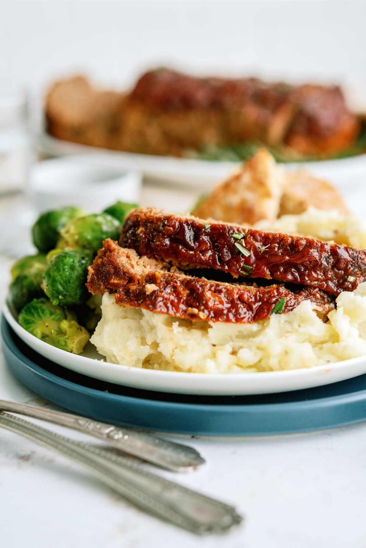 Grandma A’s Meatloaf sliced on a plate with with potatoes and brussels sprouts