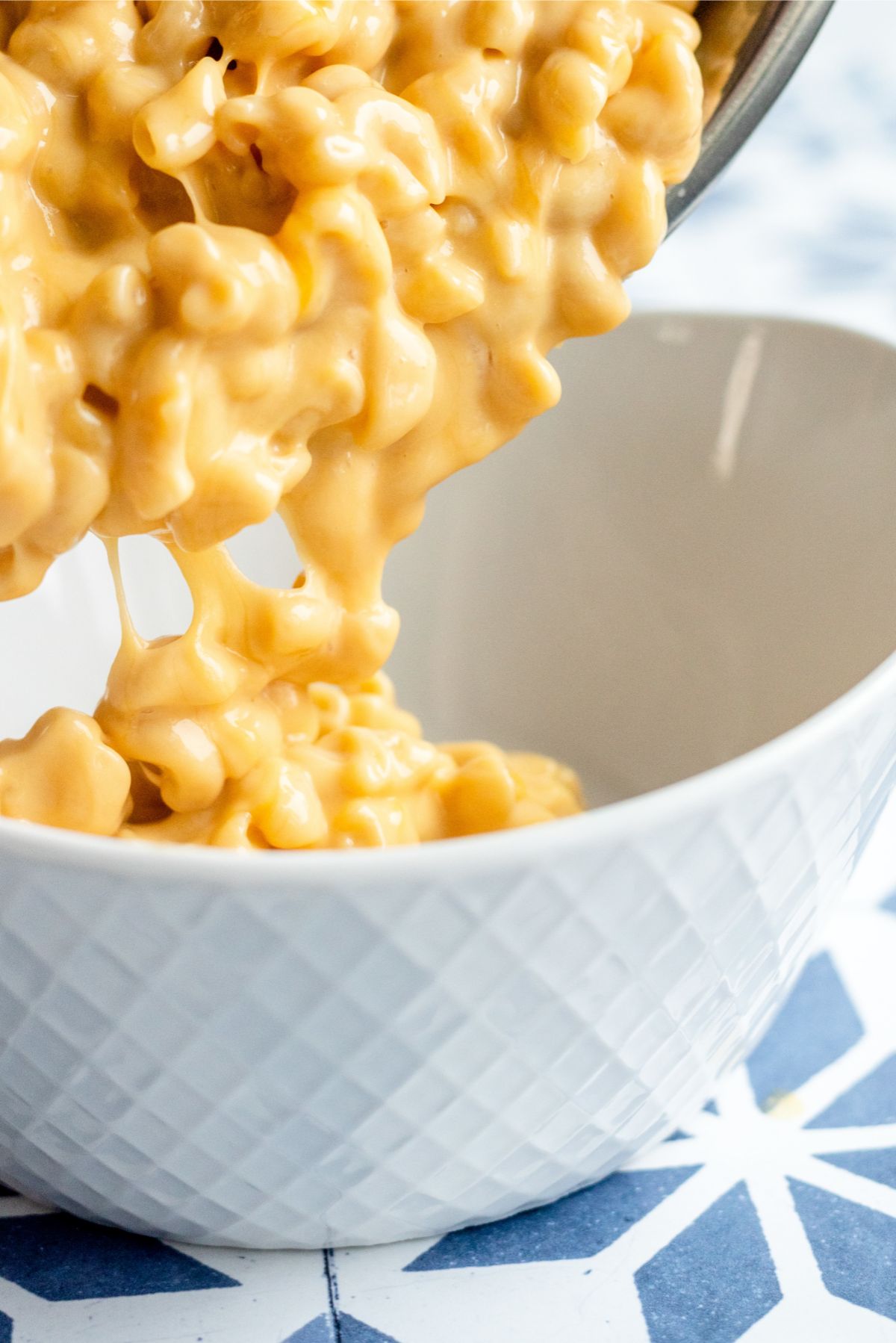Pouring Instant Pot Easy Mac and Cheese from Instant Pot into serving bowl