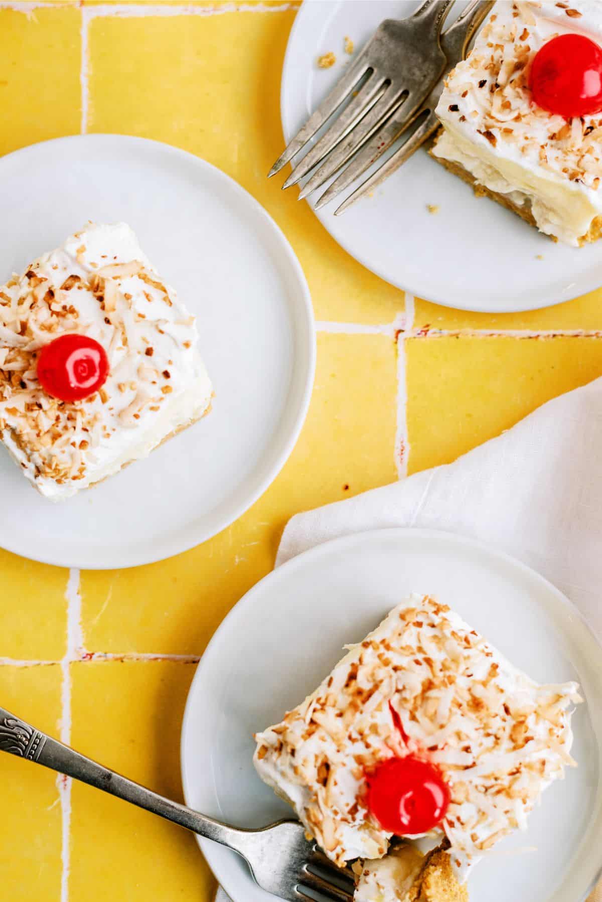 3 slices of Layered Pina Colada Dessert Recipe (Lush) on plates