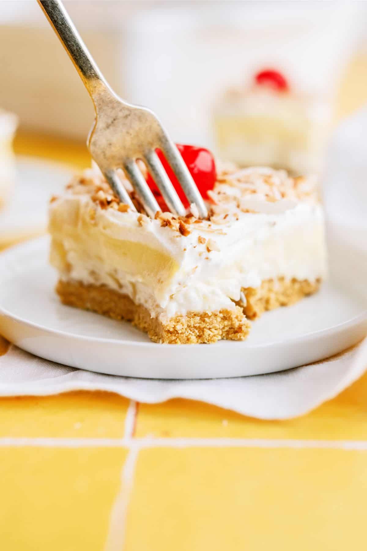 A fork slicing a bite of Layered Pina Colada Dessert Recipe (Lush)