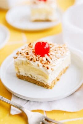 layered pina colada dessert with cherry on a plate