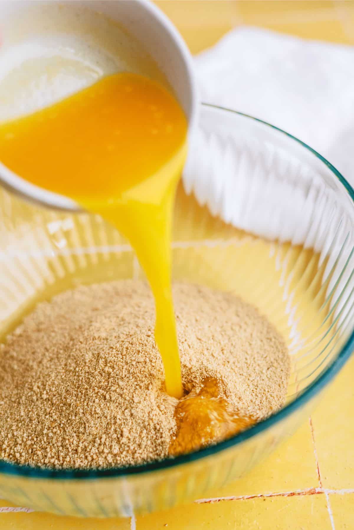 Melted butter added to a bowl with graham cracker crumbs