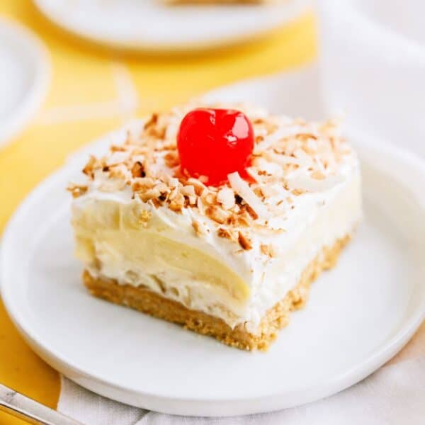 Layered pina colada dessert with cherry on a plate.
