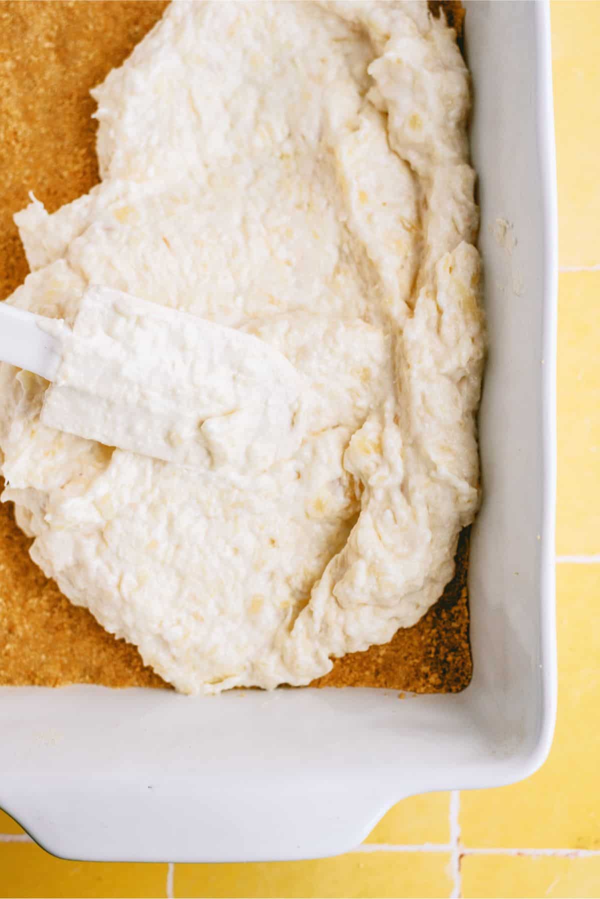 Spreading cream cheese mixture over graham cracker crust