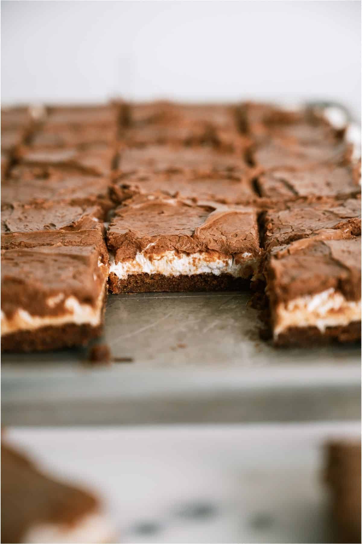 A pan of Mom's Famous Chocolate Marshmallow Brownies cut into squares with a few missing to show the inside of the brownies.