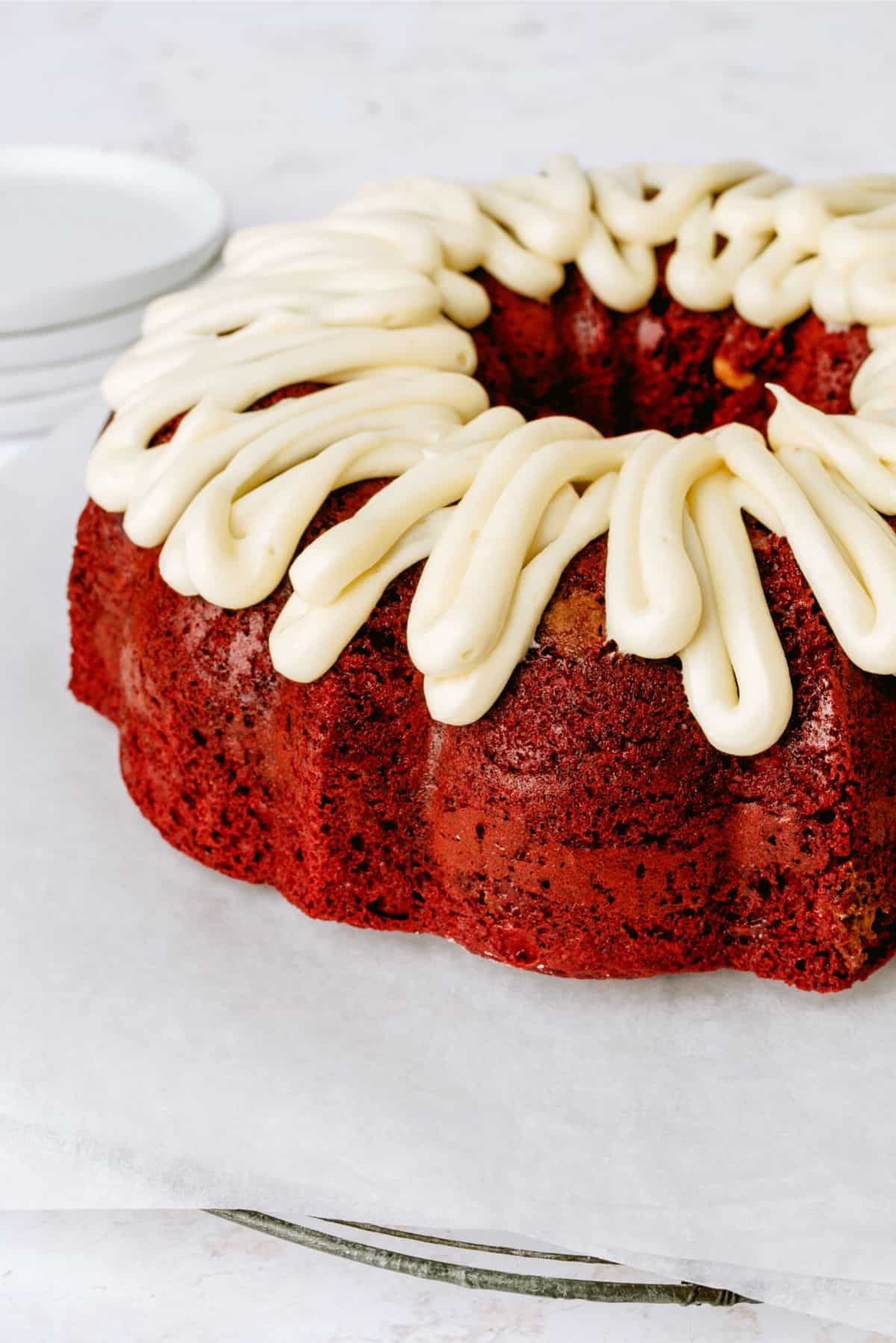Red Velvet Bundt Cake on a cake stand with frosting.