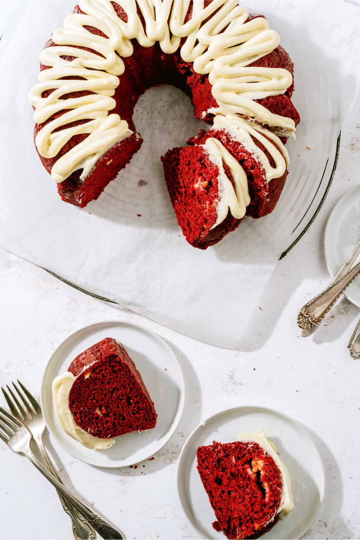 Top view of Red Velvet Bundt Cake with two slices in front of it on plates with forks.