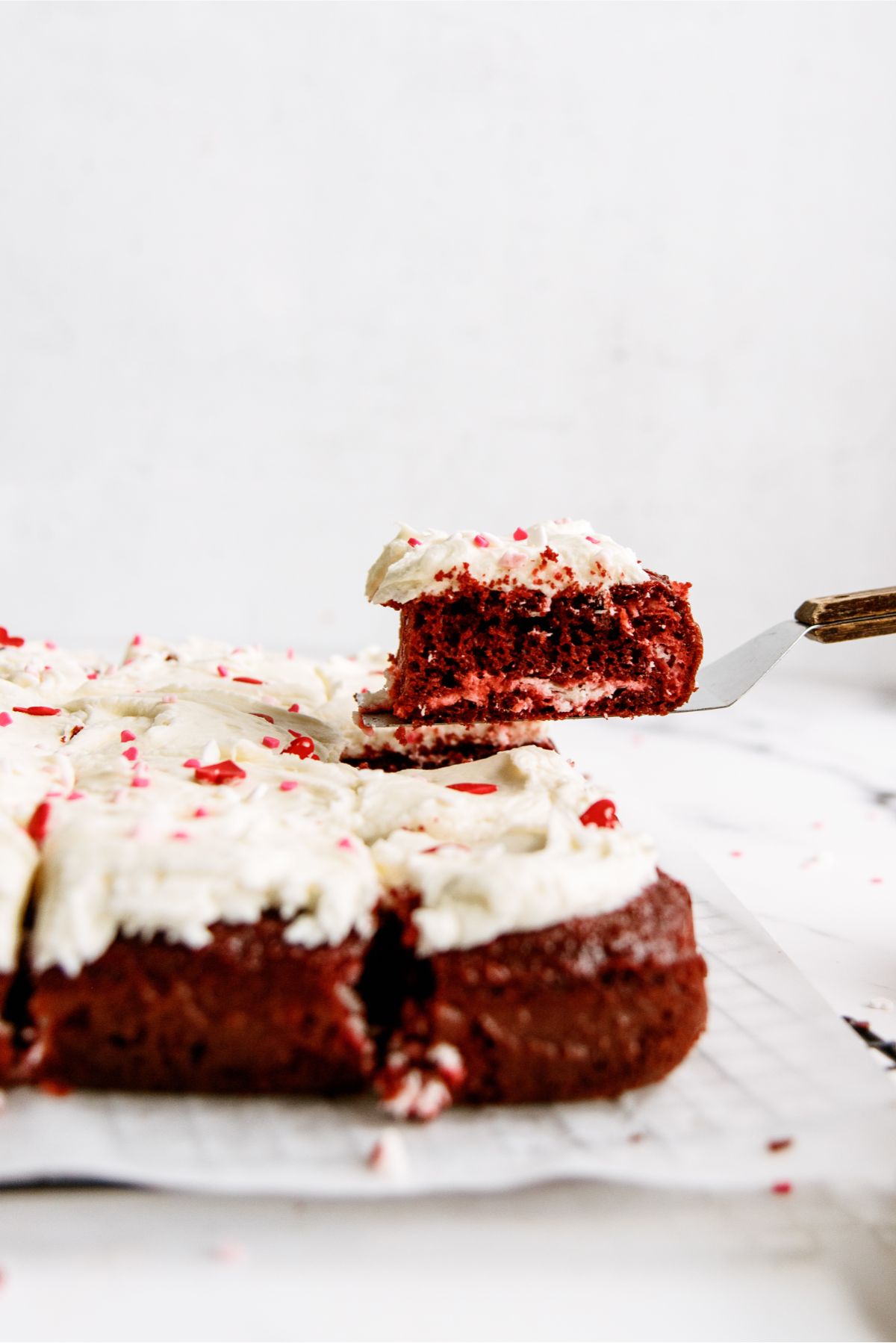 Red Velvet Cheesecake Swirl Cake sliced with a spatula lifting up one piece
