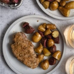 A plate with one Sheet Pan Baked Pork Chop and Potatoes.