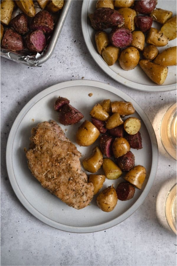 A plate with one Sheet Pan Baked Pork Chop and Potatoes.