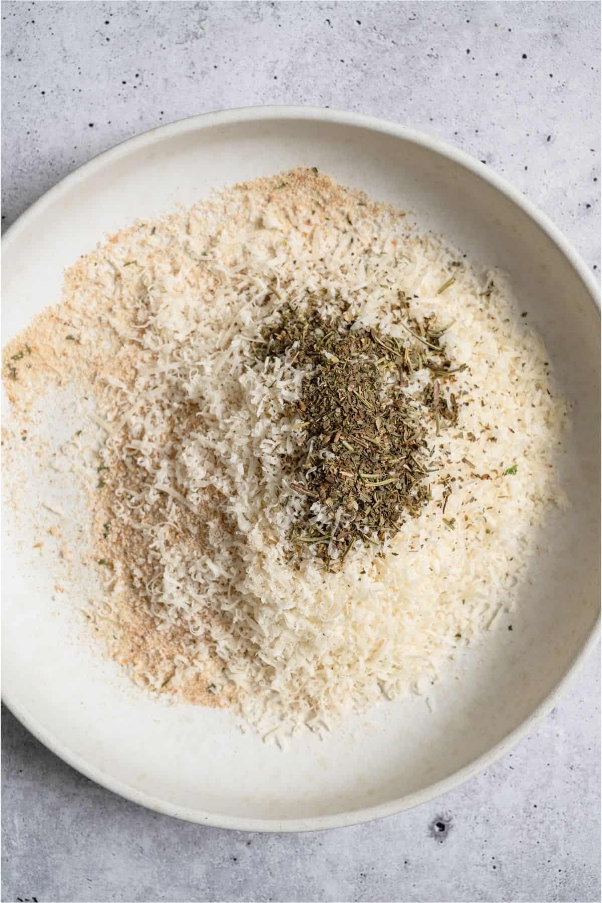 A shallow dish of breadcrumb mixture for pork chops.