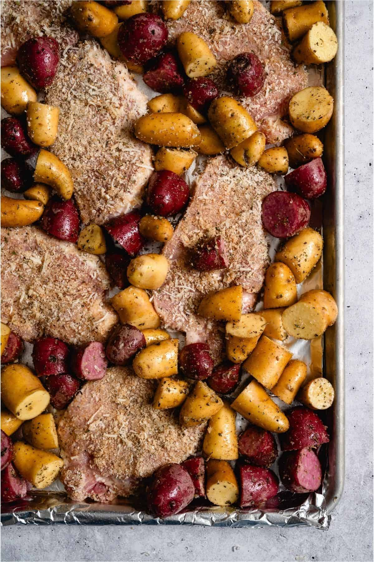 Uncooked Pork Chops and Potatoes on a sheet pan.