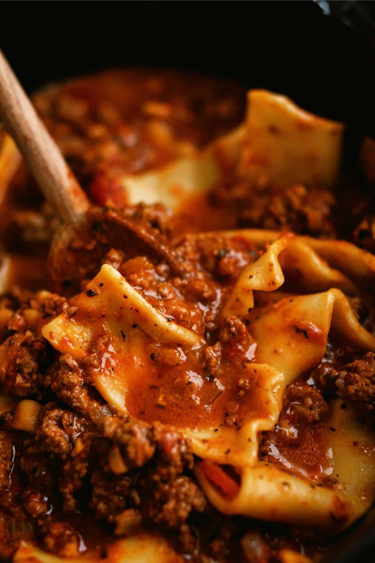 Slow Cooker Beef Lasagna Soup in the slow cooker with a wooden spoon