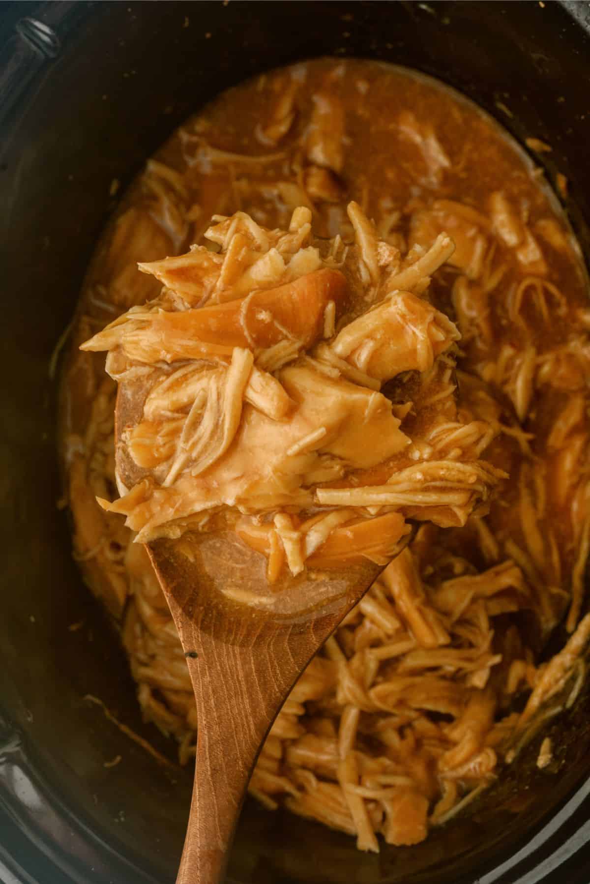 A spoonful of Slow Cooker Bourbon Chicken out of the crock pot