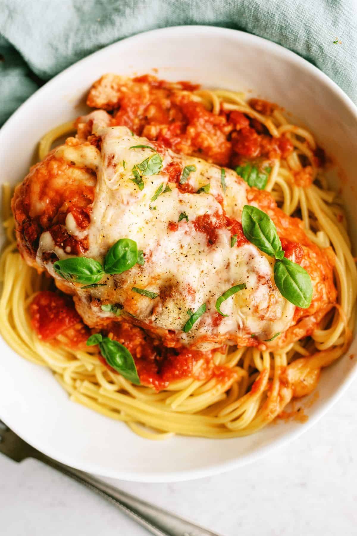 Slow Cooker Chicken Parmesan in a bowl on top of spaghetti noodles